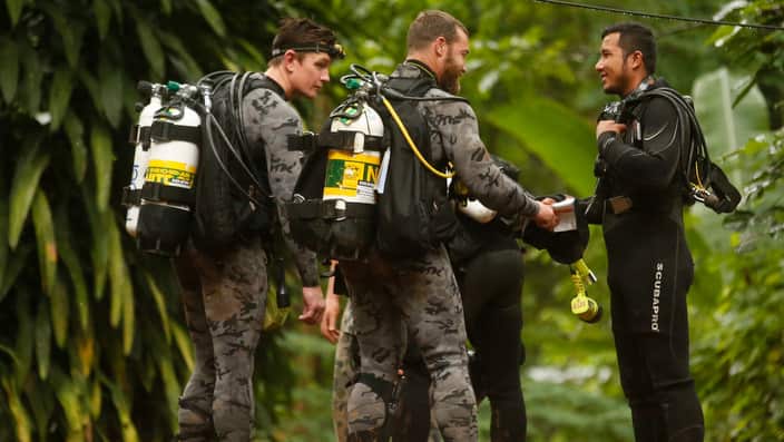 Australian Federal Police and Defence Force personnel talk to a Thai rescuer.