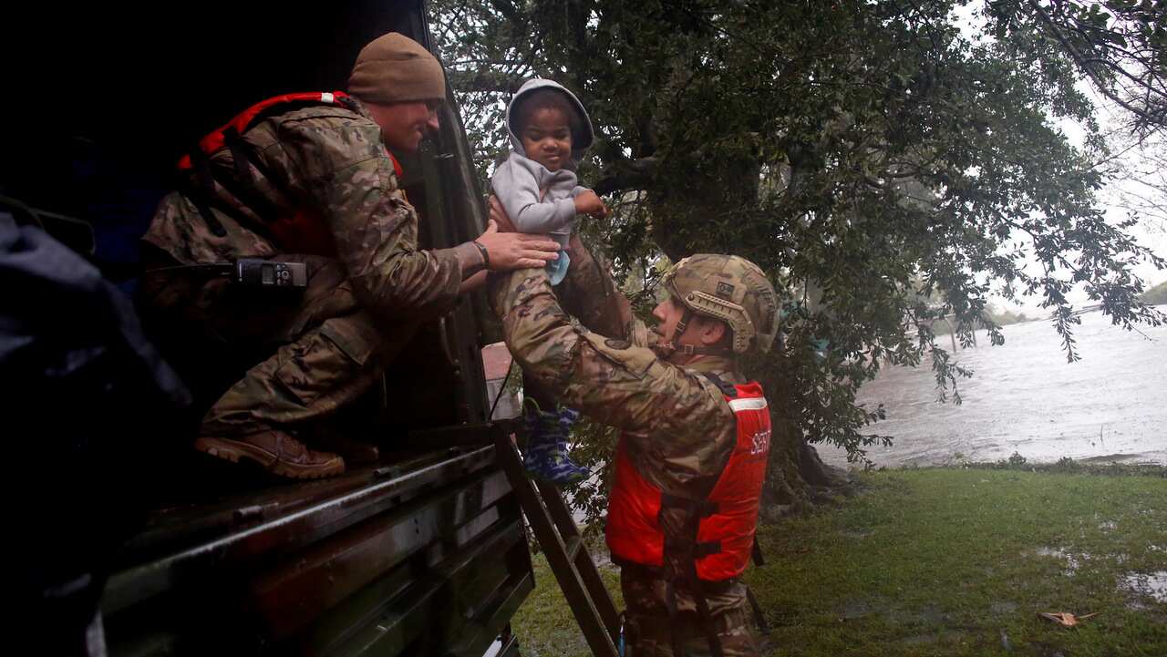 Rescue team members Sgt. Matt Locke, left, and Sgt. Nick Muhar, right, from the North Carolina National Guard 1/120th battalion, evacuates a family.