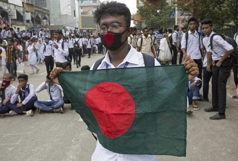 A Bangladeshi student holds the national flag during the demonstration.