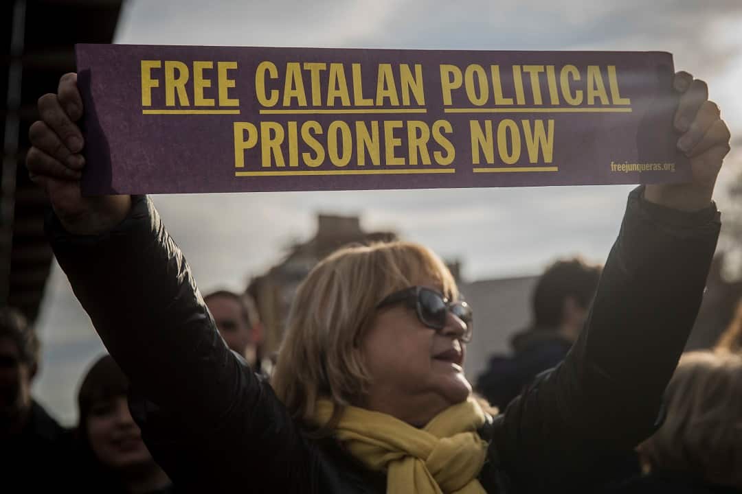 A woman holds a banner reading 'Free Catalan political prisioners now' during a protest.