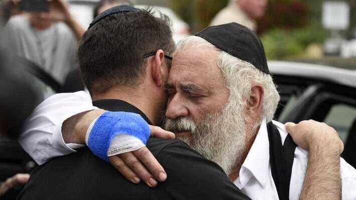 Rabbi Yisroel Goldstein (right) comforts a worshipper outside the Chabad of Poway synagogue in California.