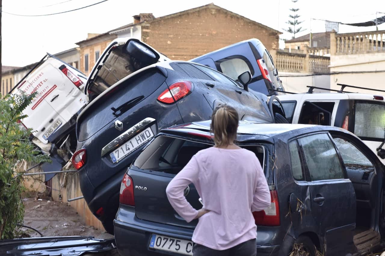 A resident looks at vehicles damaged by floods in the village of Sant Llorenc des Cardasar