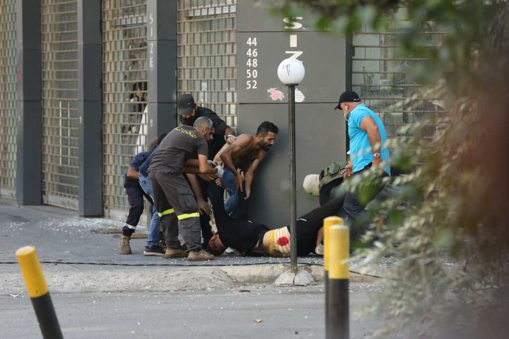 Civilians and emergency personnel rush an injured man to safety following deadly clashes in Beirut.