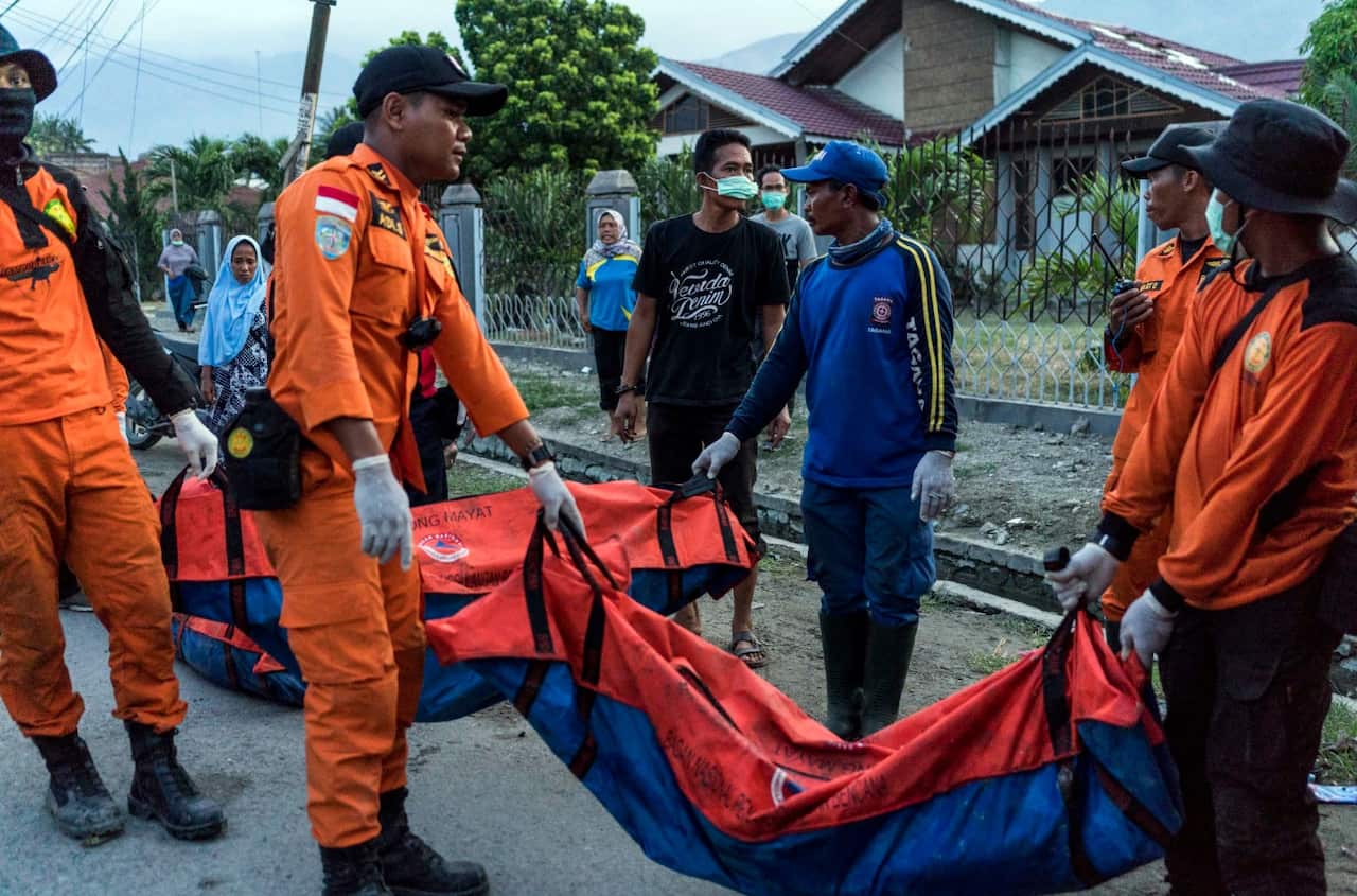 The bodies of people killed in last week's earthquake and tsunami are carried from the Balaroa neighborhood of Palu