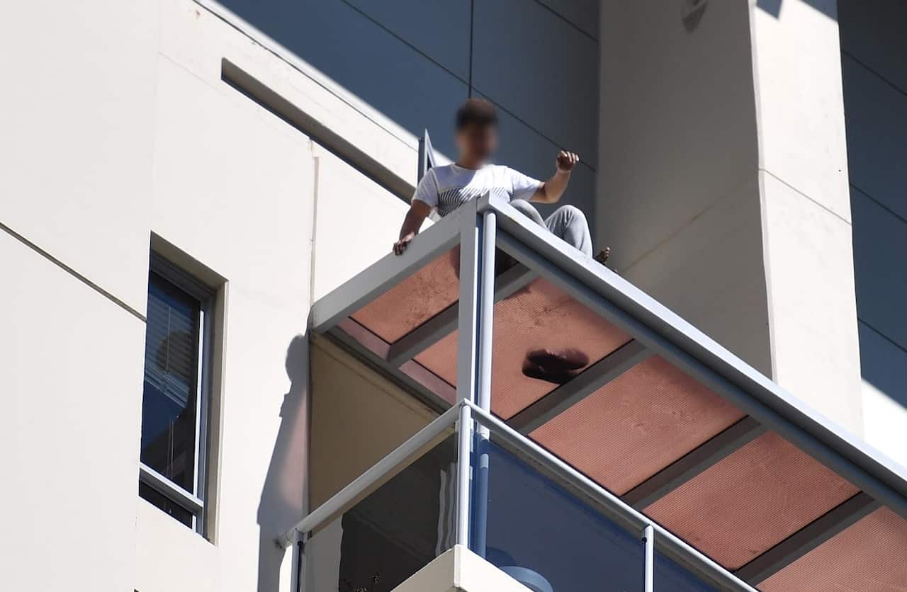 A man is seen on a ledge on an apartment building in Chatswood, Sydney, Monday, October 9, 2017. 