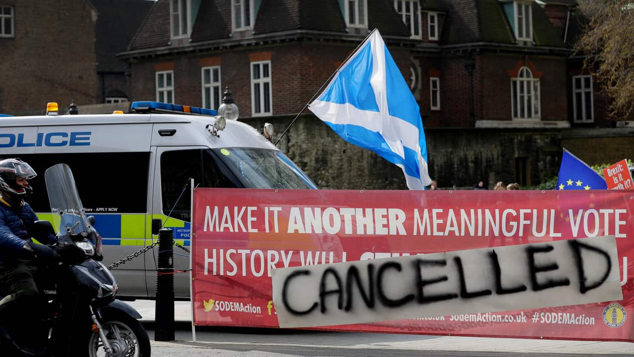 A motorcyclist passes a banner tied to railings outside Parliament in London.