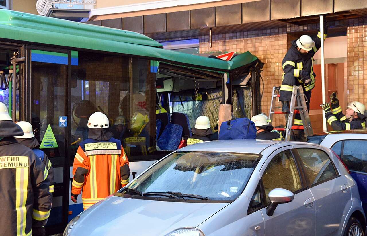 Firefighters work beside a bus sitting in the facade of a building in Eberbach near Mannheim
