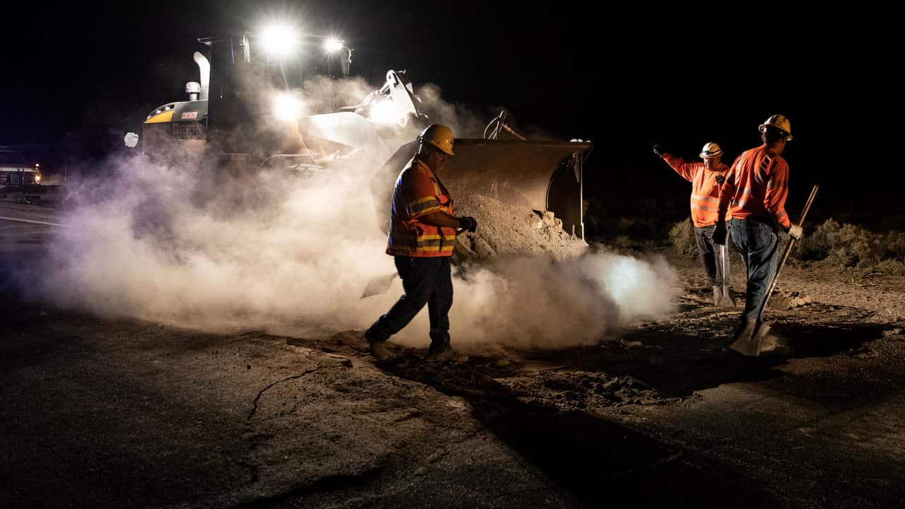 Workers of the Department of Transportation fill the the large holes left in the road after an earthquake.