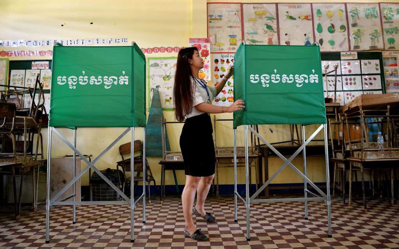 A member of the Cambodian National Election Committee (NEC) prepares a voting booth at a polling station in Phnom Penh on July 28, 2018