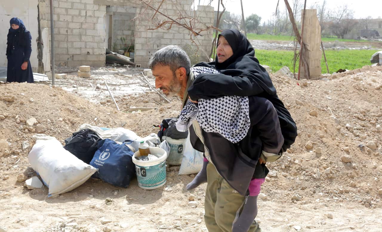 A syrian man carries his mother as thousands leave rebels-held Eastern Ghouta. 