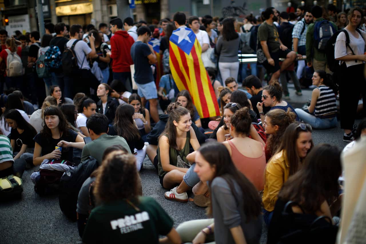 Protestors sit on the ground blocking a street in Barcelona, Spain, after the court's decision.