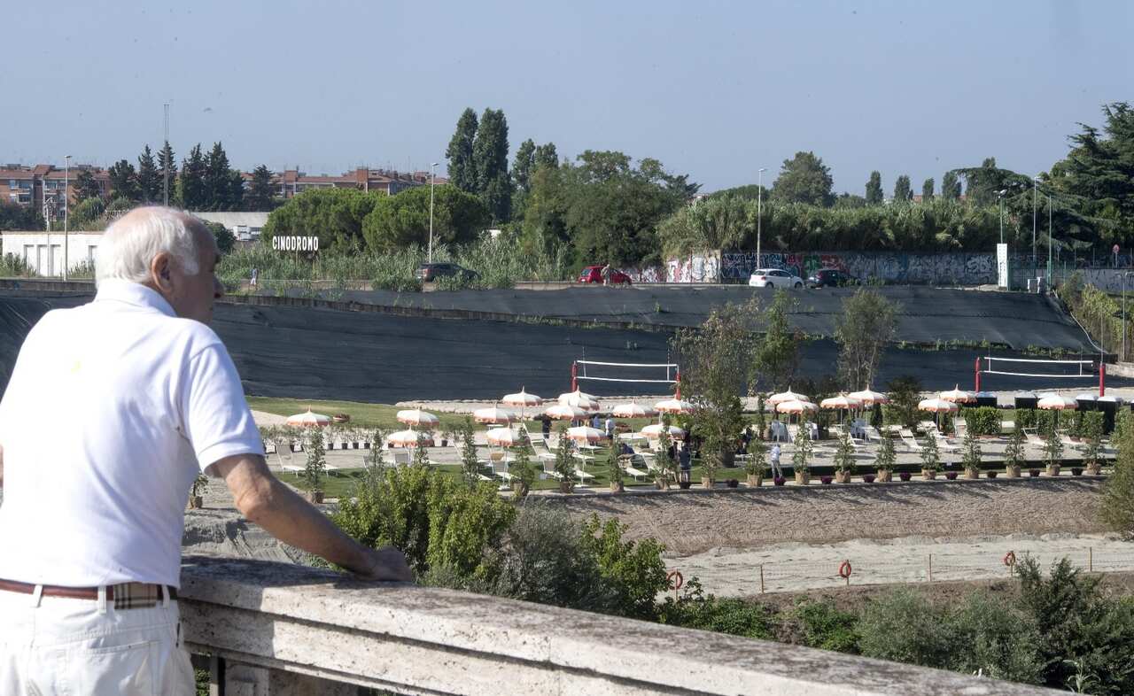 A man (L) standing on the Marconi bridge looks at sunbeds and parasols set up for visitors of the 'Tiberis' beach along the Tiber river