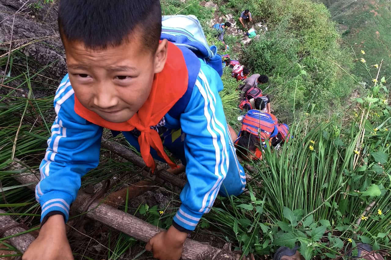 A child with a worried look on his face scales the ladder, a row of children climb behind him.