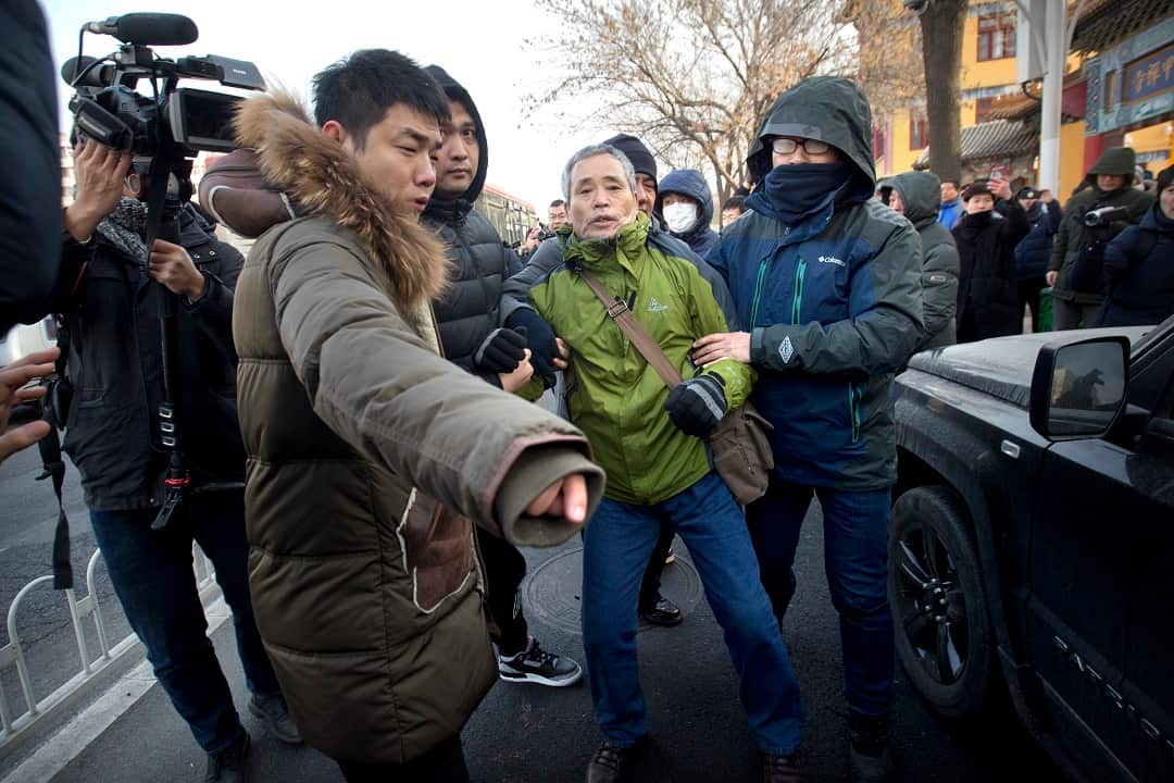 Plainclothes security officers take away a supporter of Chinese human rights lawyer Wang Quanzhang.