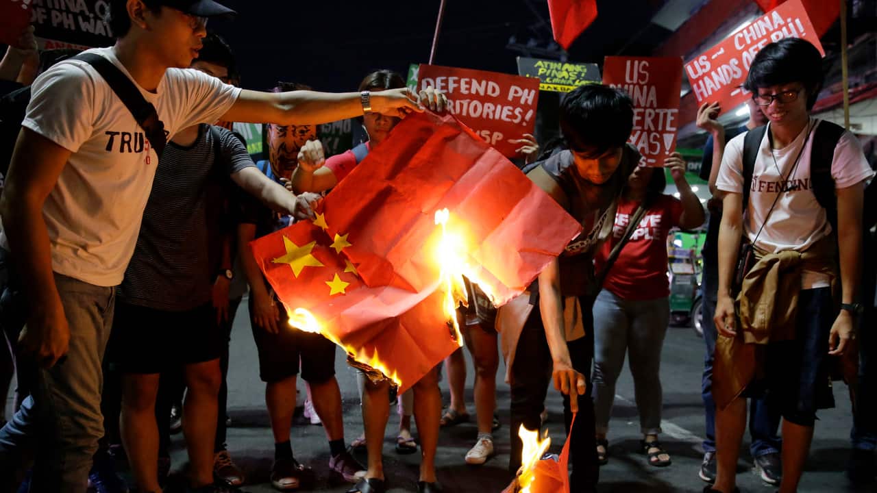Student rallyist burn a Chinese flag as they protest against the visit of Chinese President Xi Jinping.