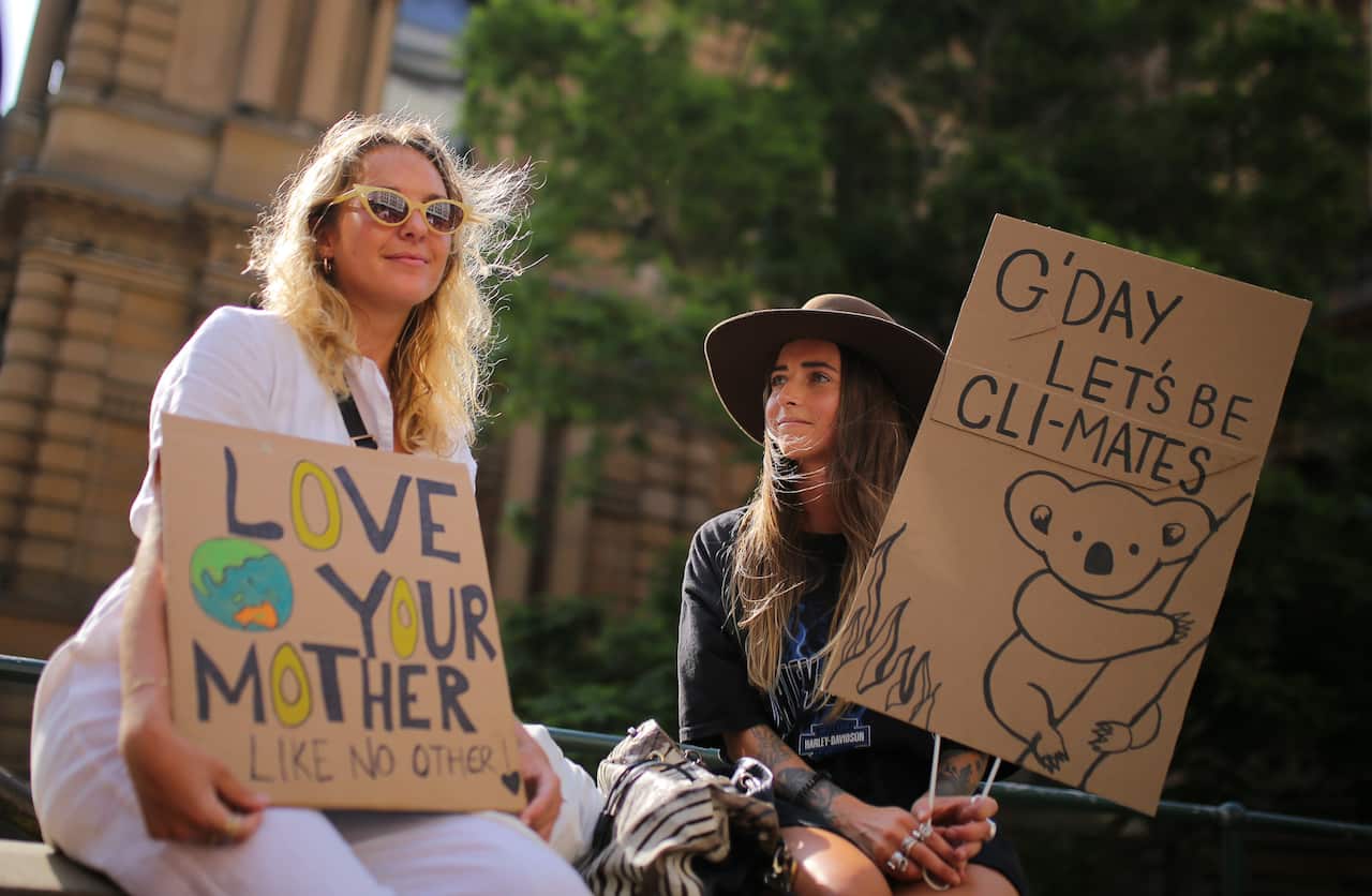 Protesters hold placards during the 'Sack ScoMo!' climate change rally in Sydney.Protesters hold up their signs ahead of the rally in Sydney.