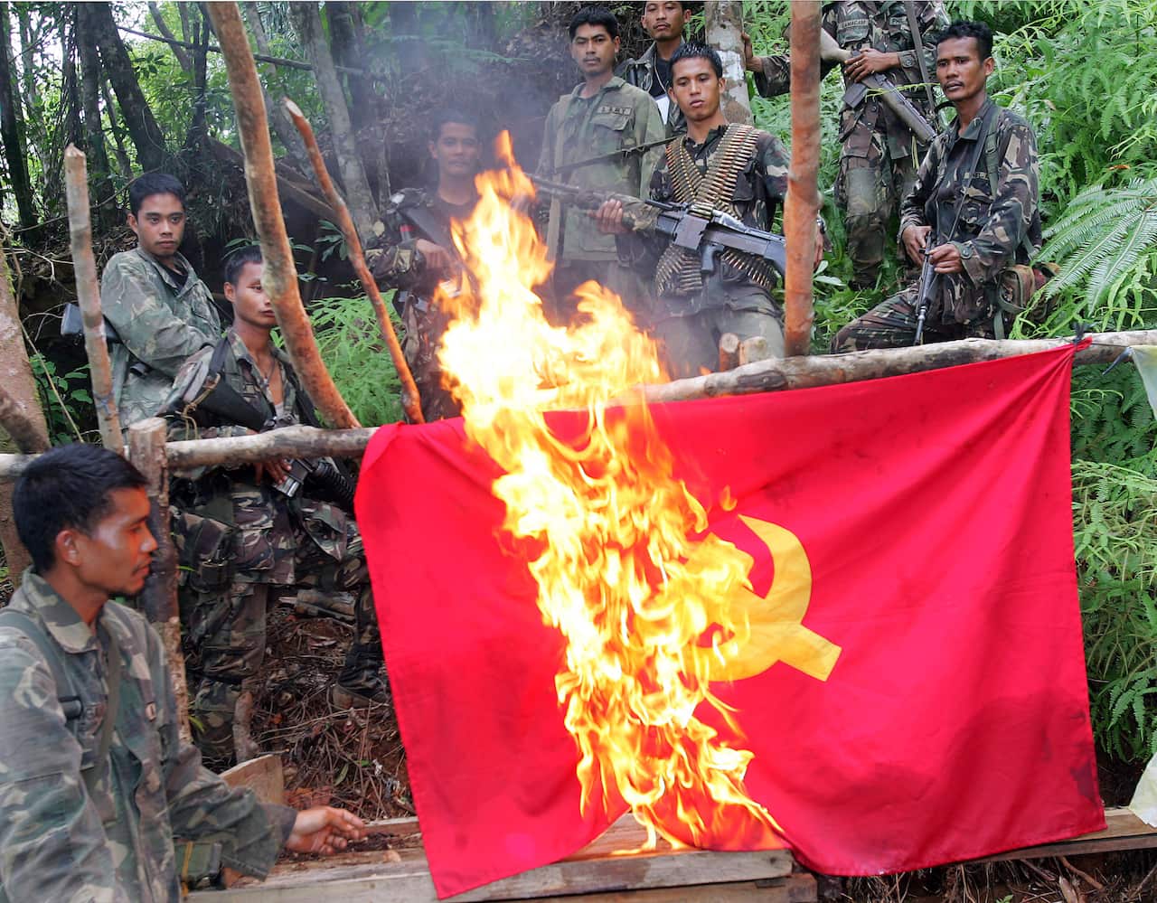Philippine Army soldiers watch as they burn a communist flag in an abandoned rebel camp in the mountainous area of General Nakar.