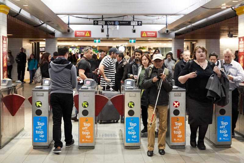 Commuters pass through barriers at a train station.