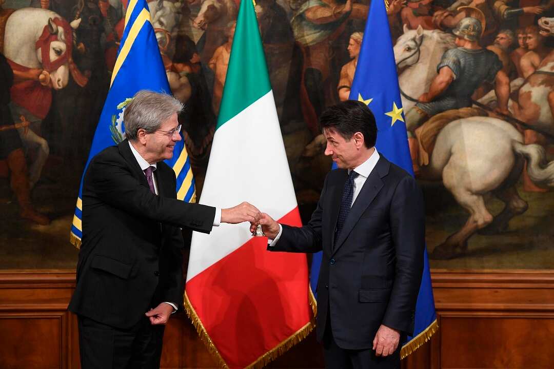 Italian outgoing Premier Paolo Gentiloni, hands over the cabinet minister bell to new Premier Giuseppe Conte during the handover ceremony at Chigi Palace Premier's office, in Rome, Friday, June 1, 2018. (Claudio Peri/ANSA via AP)