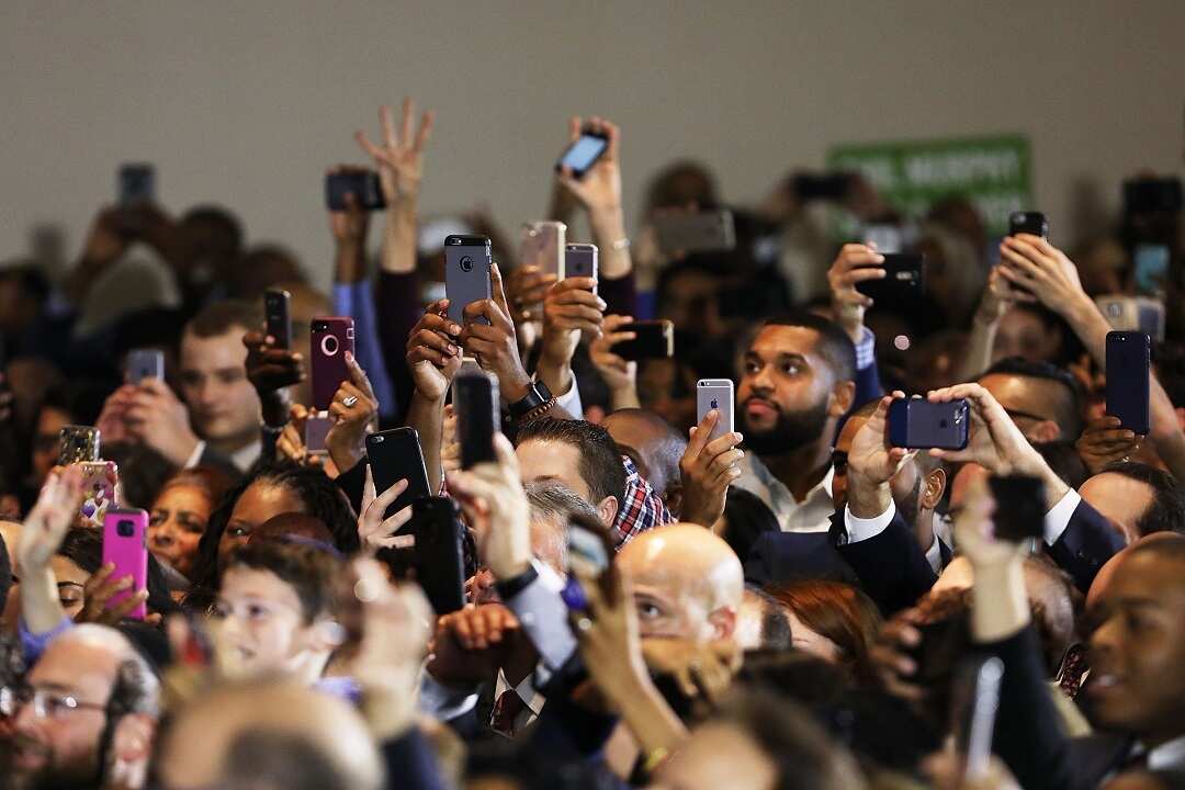 People cheer and take pictures as former US President Barack Obama speaks at a rally in support of Democratic candidate Phil Murphy.