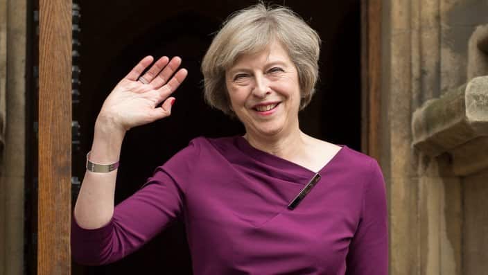 Theresa May waves to members of the media outside of The Houses of Parliament in London.