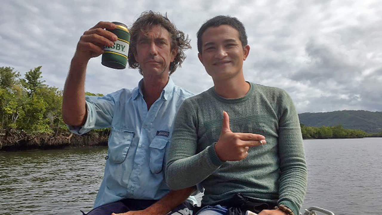 A local fisherman (left) treating one of two suspected asylum seekers to a tour after being found on the banks of the Daintree River.