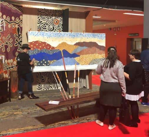 Indigenous artist Danielle Mate Sullivan painting in front of visitors at the furniture fair in Milan.