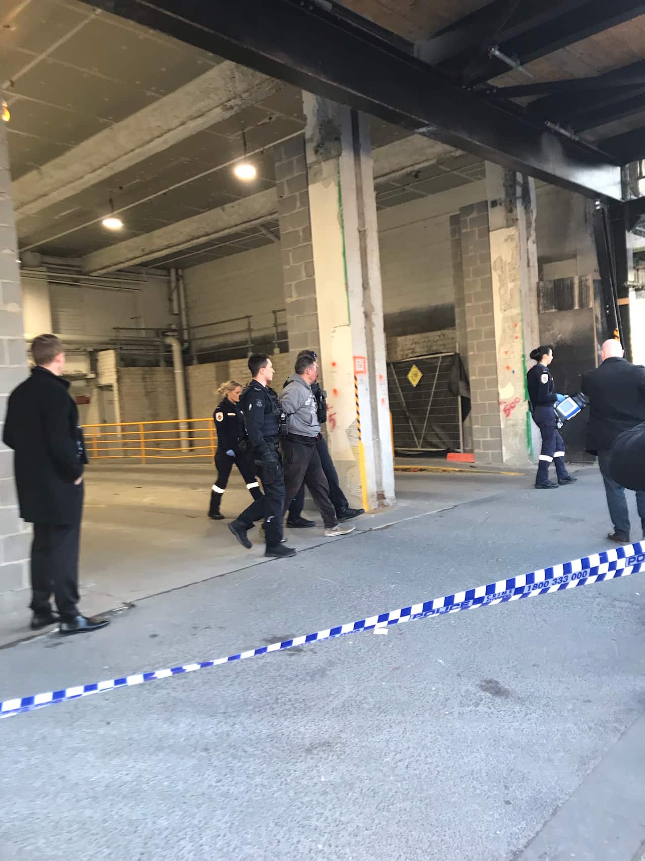 Jonathan Dick, pictured with police, is wanted for questioning over the February 2017 murder of David Dick at Westfield Doncaster.