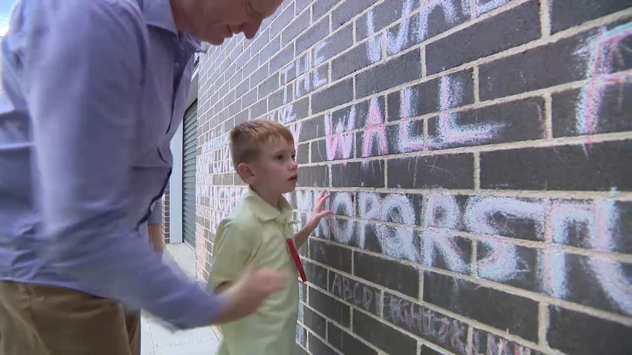 Luke Rapley with his father Sean look at the alphabet written in chalk on the "Luke Rapley wall for fun"