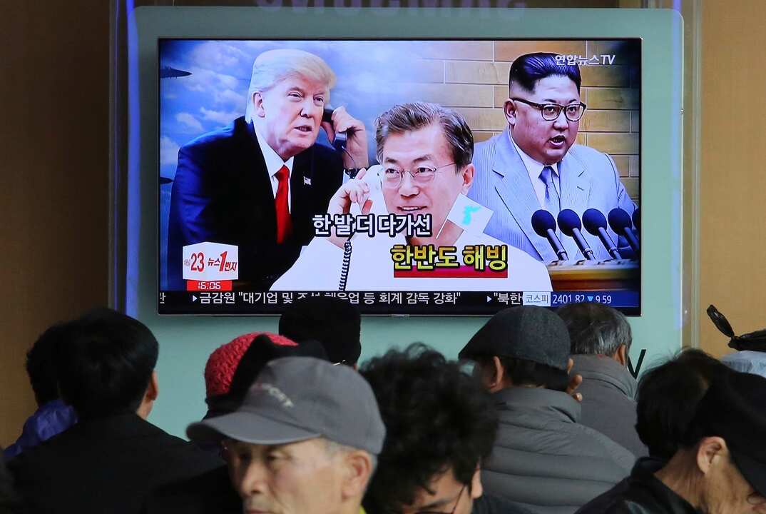 People watch a TV screen showing images of Kim Jong-un, right, Moon Jae-in, centre, and Donald Trump at the Seoul Railway Station.