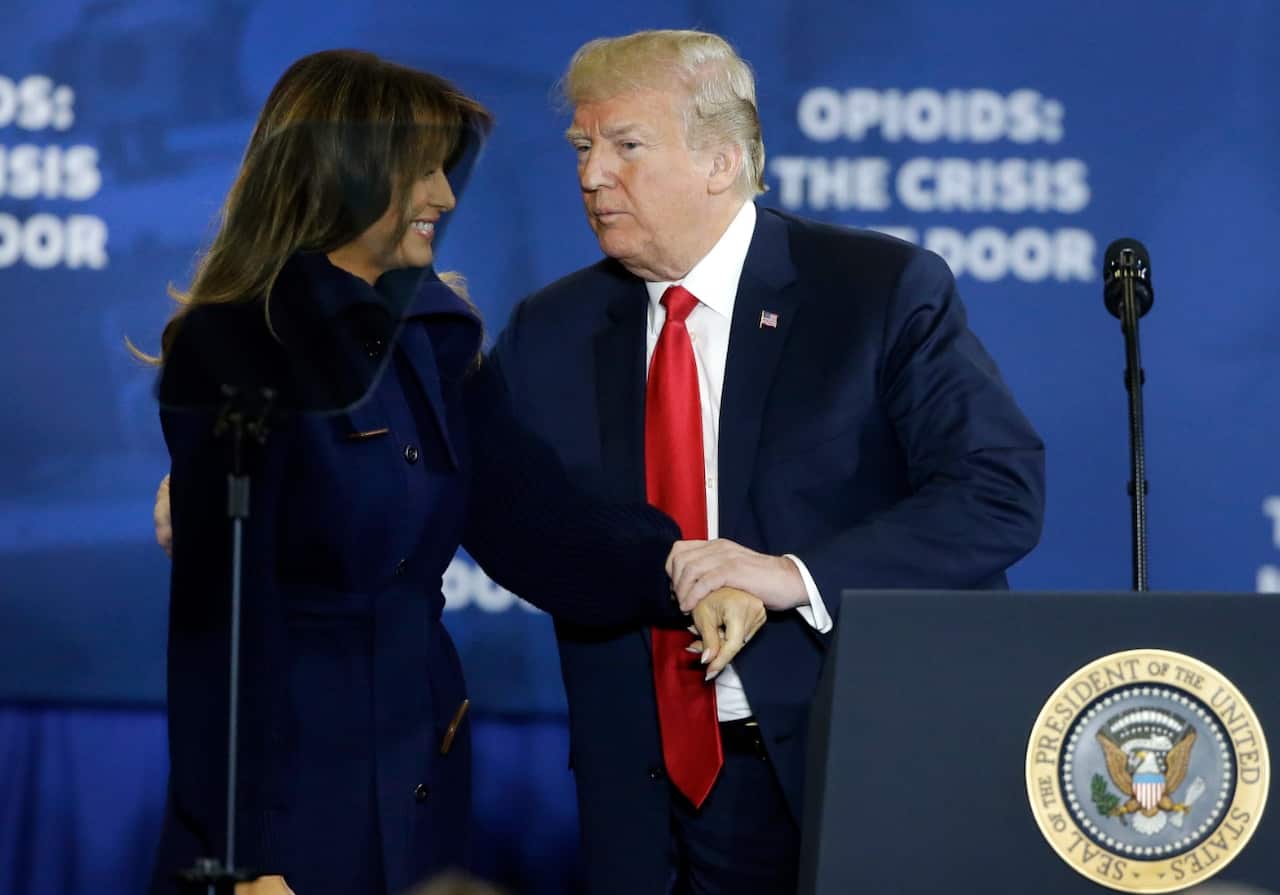 President Donald Trump clasps hands with first lady Melania Trump as he takes the podium to speak about his plan to combat opioid addiction