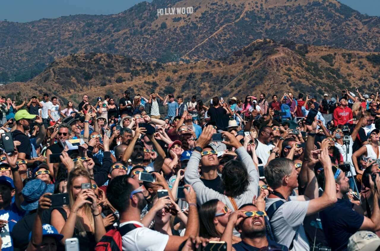 A large crowd gathers in front of the Hollywood sign at the Griffith Observatory to watch the solar eclipse in Los Angeles Monday, Aug. 21, 201 (AAP)