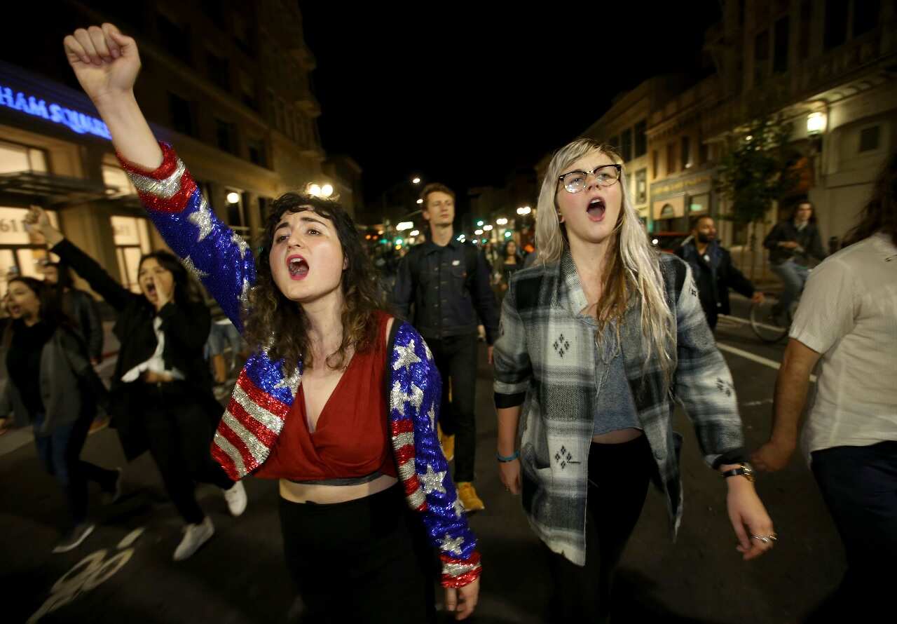 Madeline Lopes, left, and Cassidy Irwin, both of Oakland, march with other protesters in downtown Oakland, Calif., early Wednesday, Nov. 9, 2016.