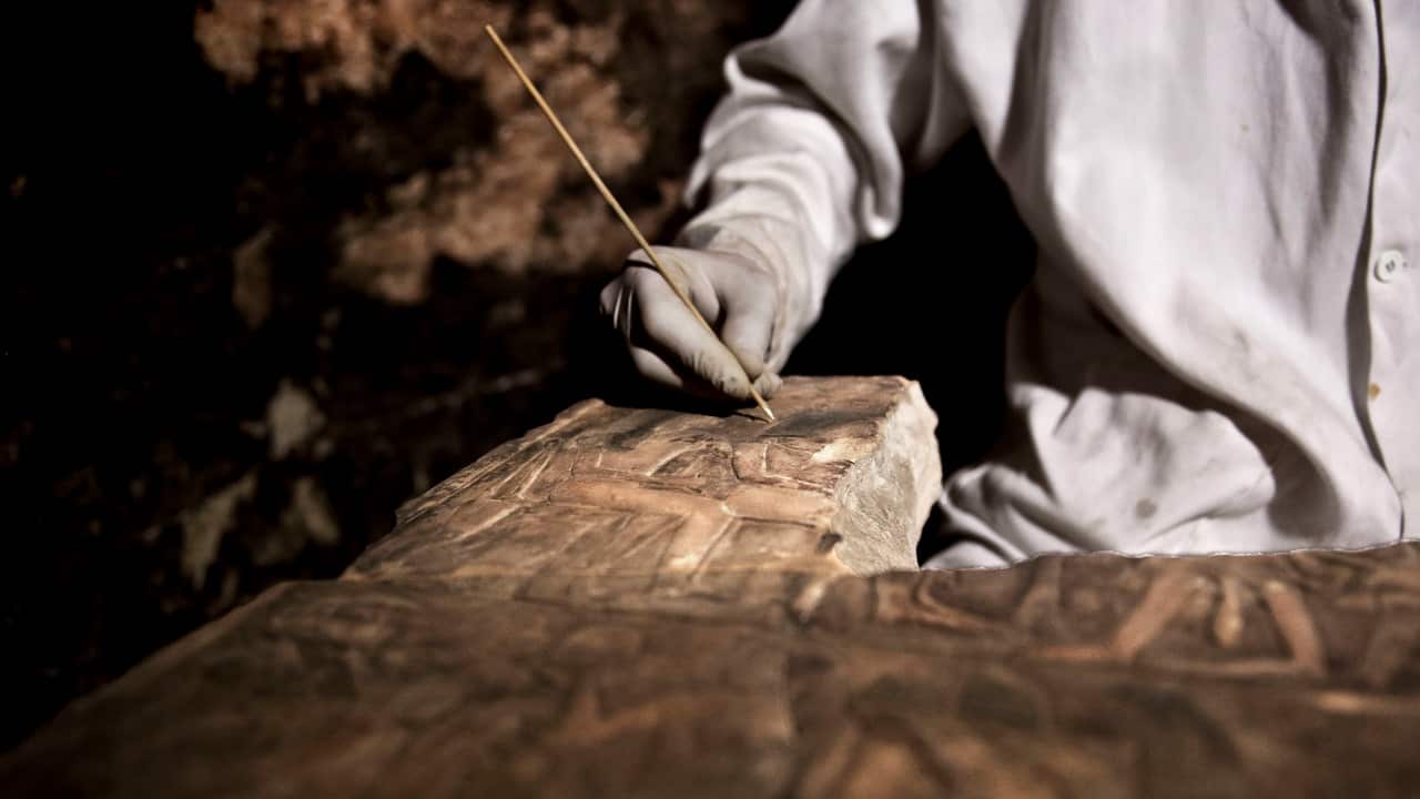 An archaeologists works on an artifact inside a tomb, at an ancient necropolis near Egypt's famed pyramids in Saqqara, Giza, Egypt.