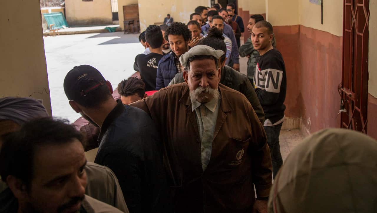 People stand in line to cast their vote during the referendum on draft constitutional amendments, at a polling station in Cairo.