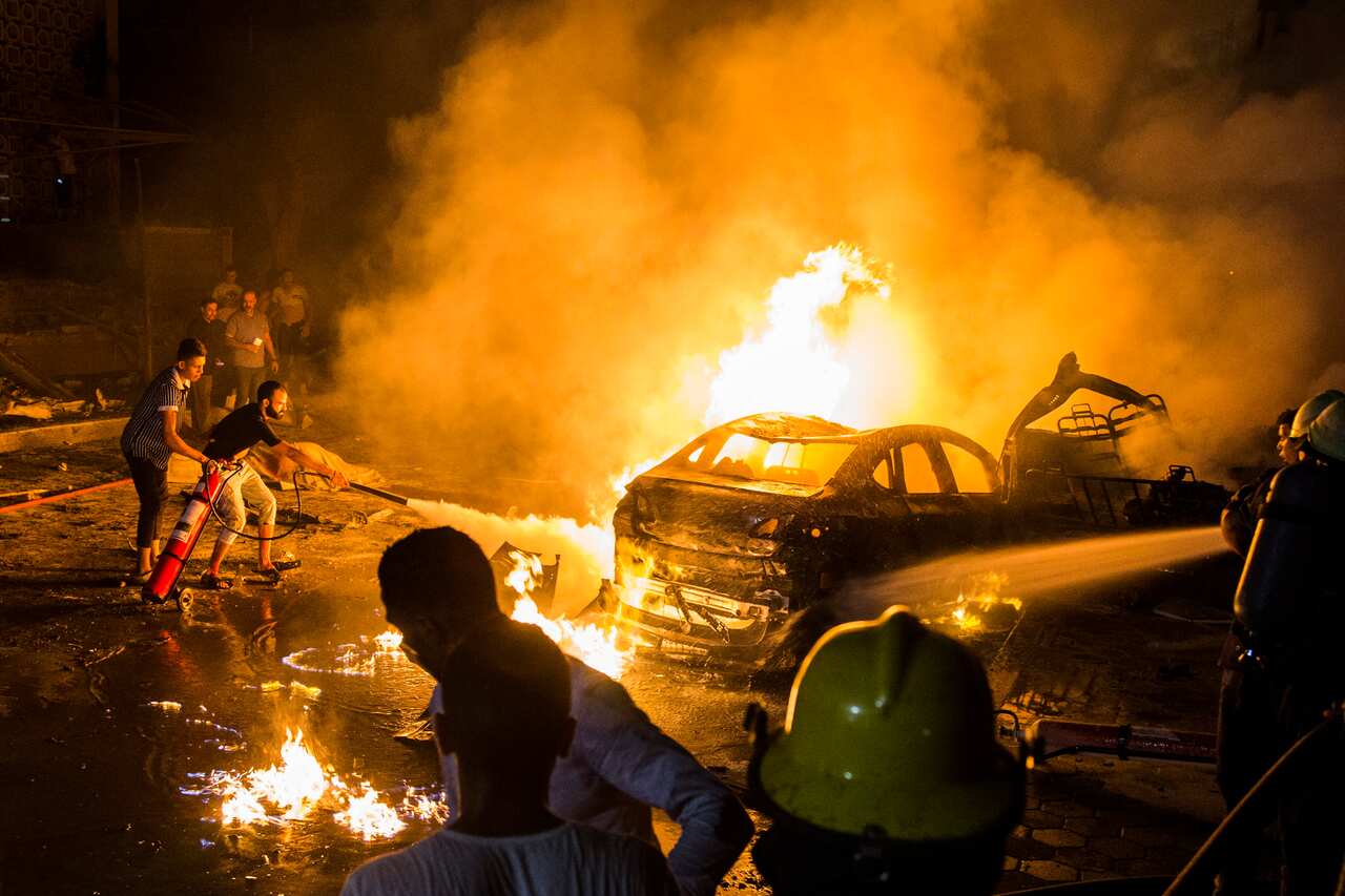 People extinguish a fire from a blast inside the National Cancer Institute in Cairo.