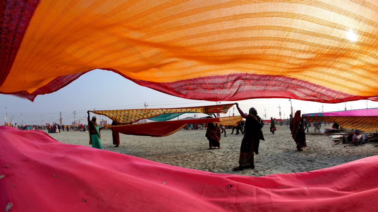 Hindu devotees dry their clothes after taking  spiritual cleansing dips at the Sangam.