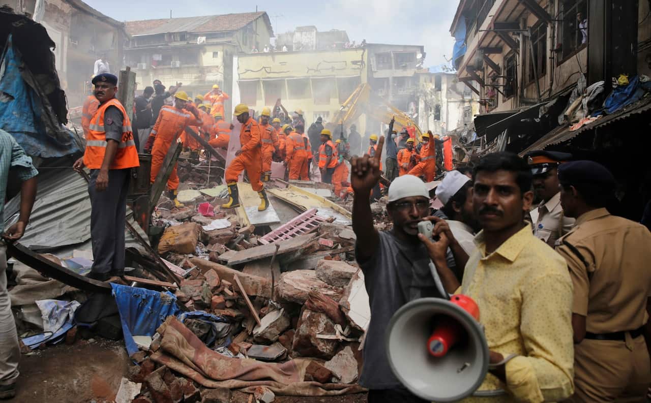A rescue worker makes an announcement on a loudspeaker at the site of a building collapse in Mumbai, India, Thursday, Aug. 31, 2017.