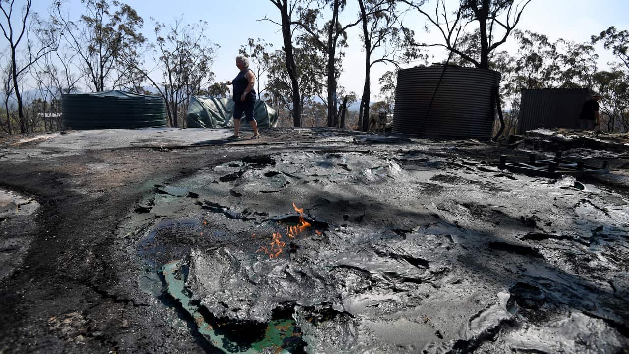 Jeanette Schwindt inspects her burnt out water tanks after a bushfires swept through the area the day before in Mount Larcom, Queensland.