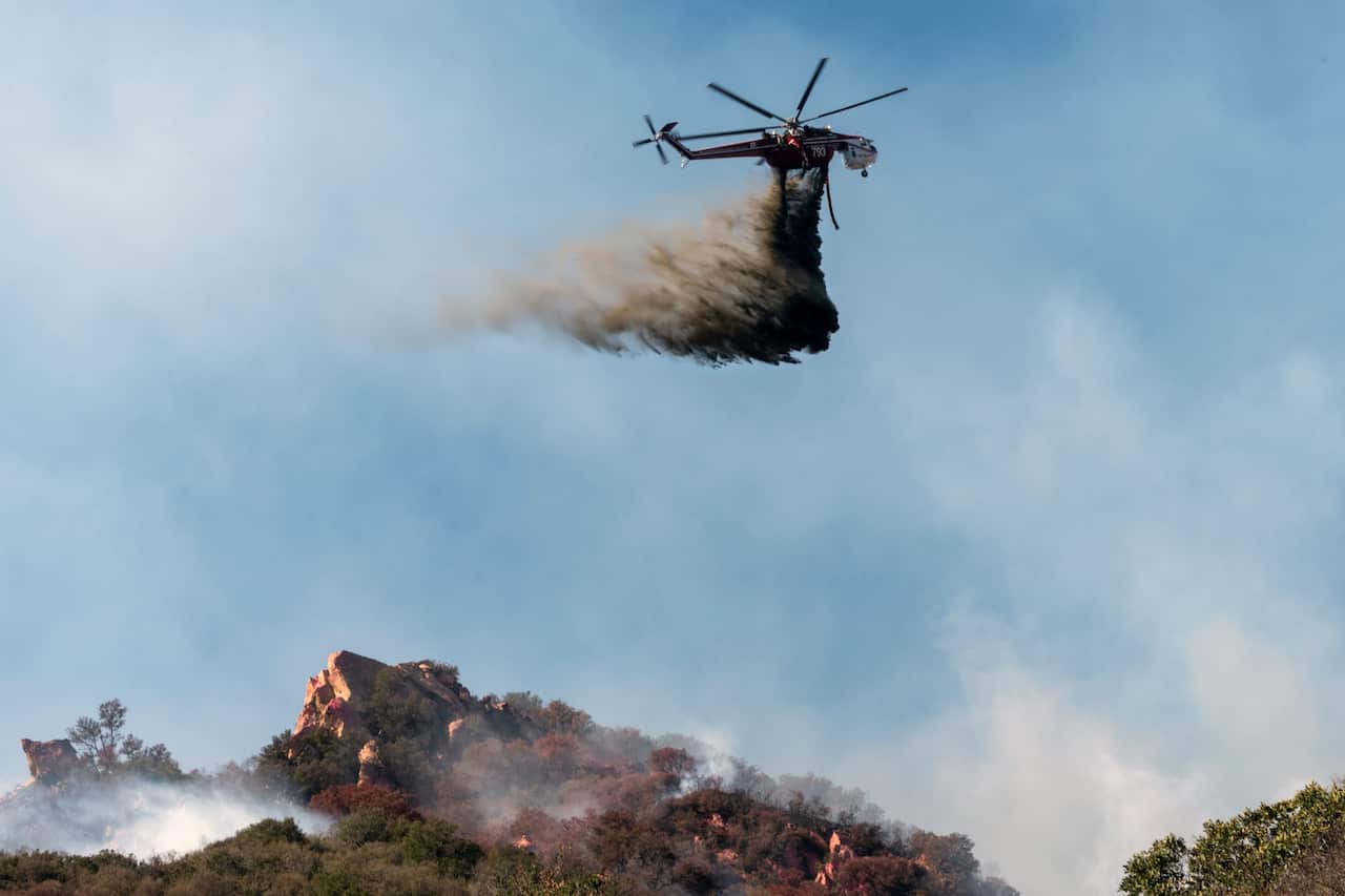 A helicopter makes a water drop on the Woolsey Fire near Malibu, California