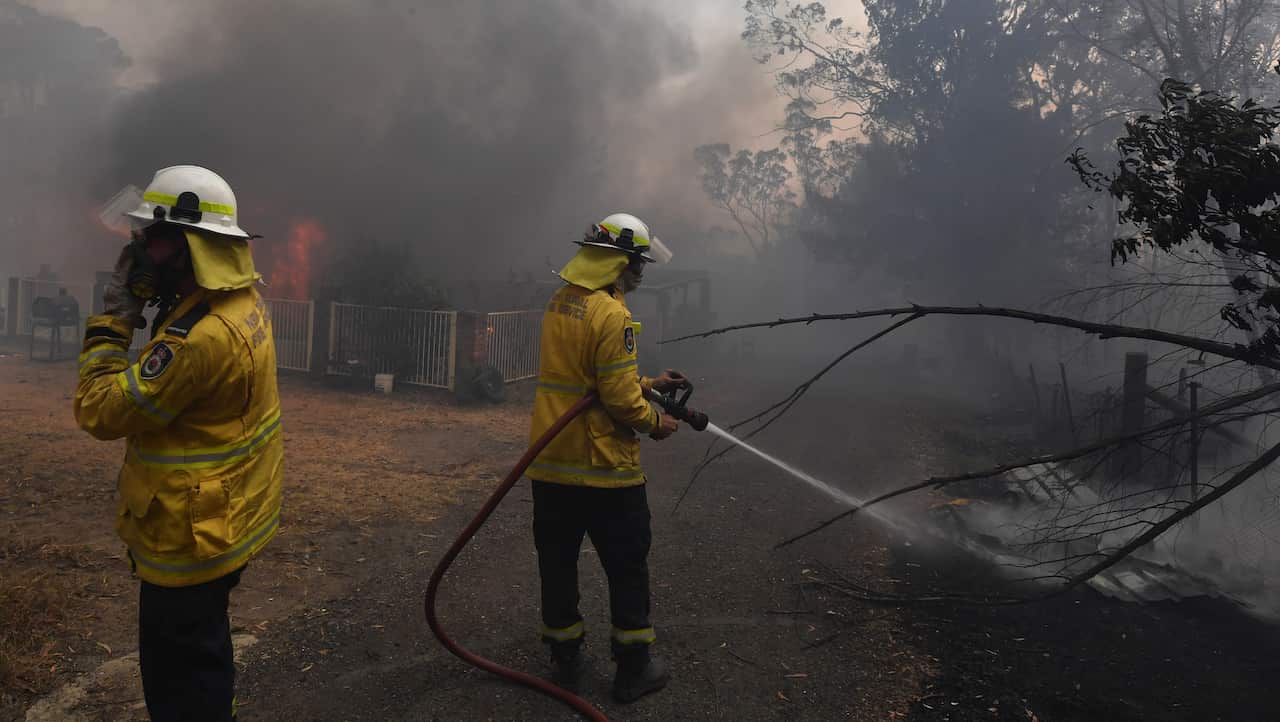 Firefight douse a home lost to a bushfire on Hassall Road in Buxton, New South Wales.
