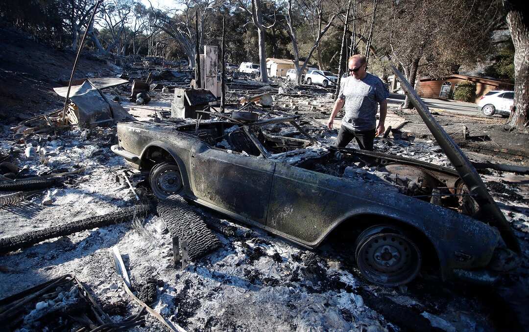 David Spence from the UK looks at a burned out vintage sports destroyed in the fire.