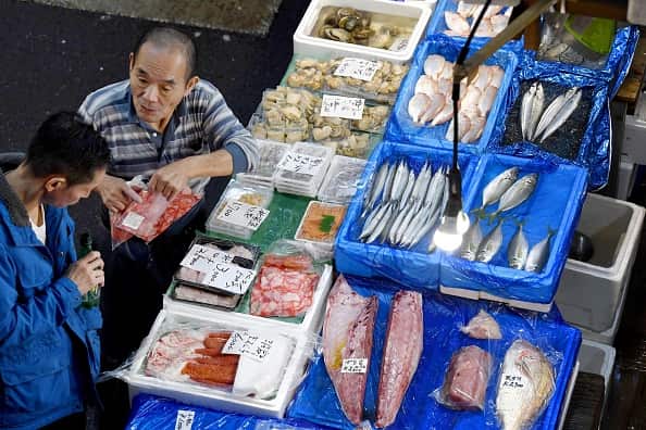 An intermediate wholesaler chats with a customer at his fish store in Tsukiji fish market ahead of the relocation.