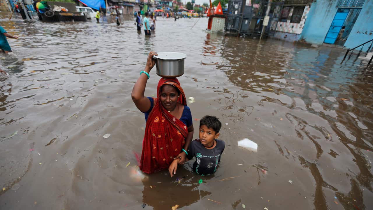 An Indian woman and a child wade past floodwaters after heavy rainfall in Ahmadabad.