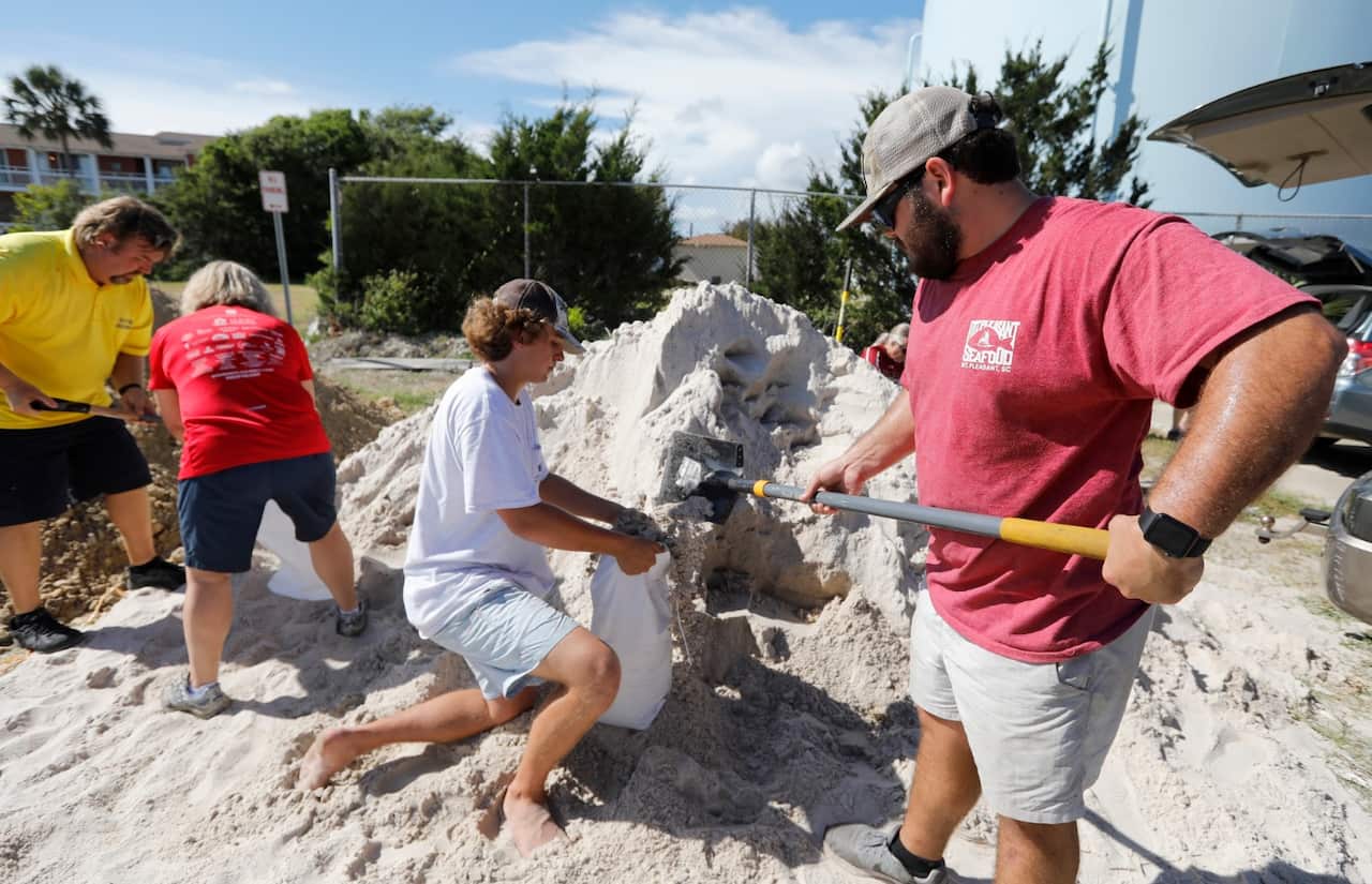 Walker Townsend, at right, from the Isle of Palms, S.C., fills a sand bag while Dalton Trout, in center, holds the bag at the Isle of Palms municipal