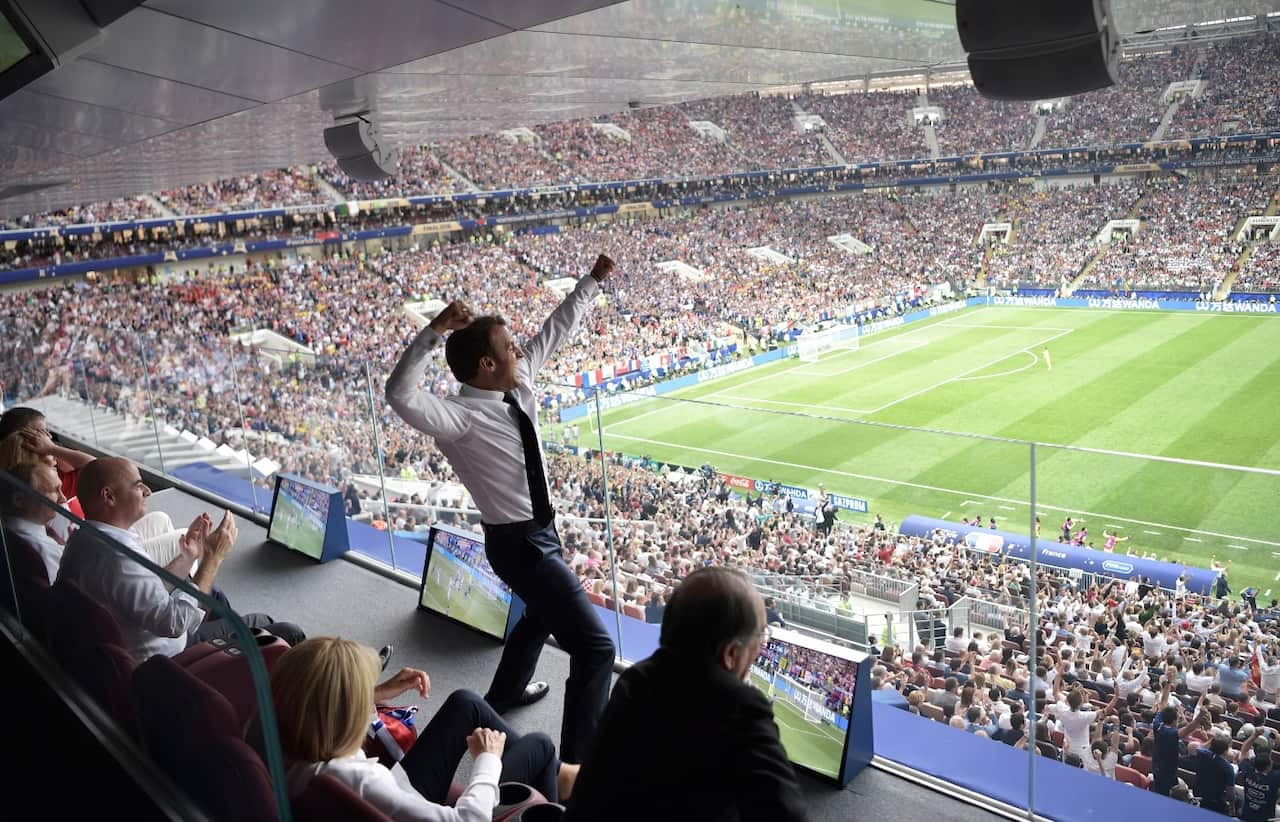 French President Emmanuel Macron (C) reacts as Russian President Vladimir Putin (L) and FIFA President Gianni Infantino (2-L)