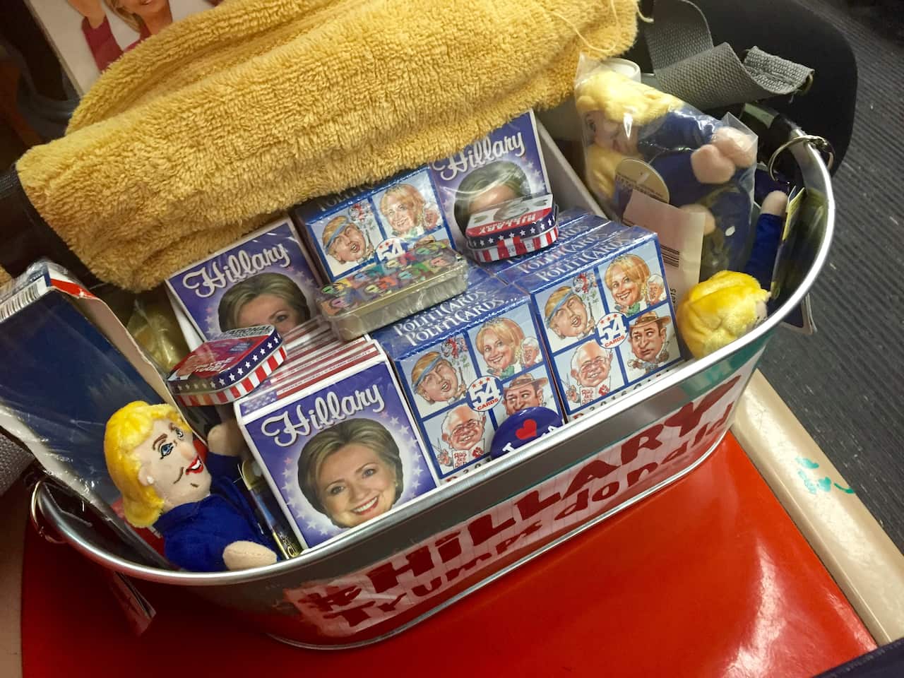 A metal bucket with straps which is full of hillary clinton merchandise.