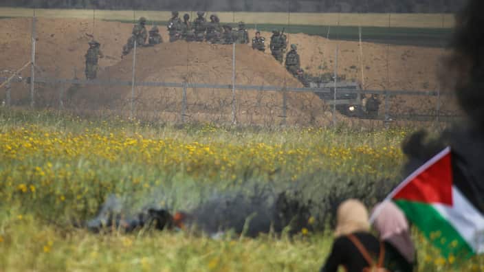 Palestinian protesters wave their national flags in front of Israeli security during protests. 