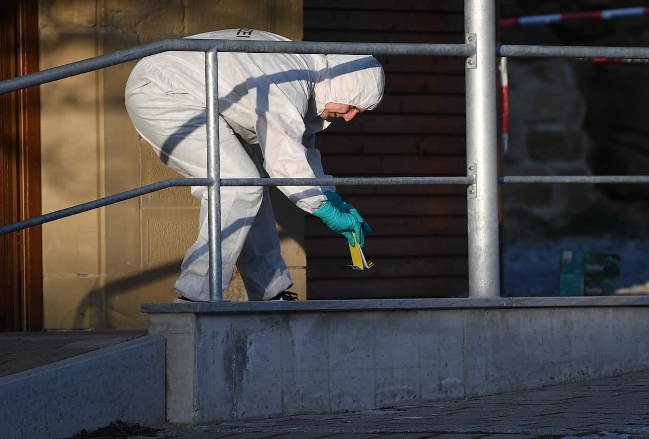 A forensic officer collects evidence at the scene following the fatal shooting. 