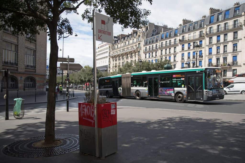 A bus rides past a 'uritrottoir' public urinal on August 13, 2018, in Paris.